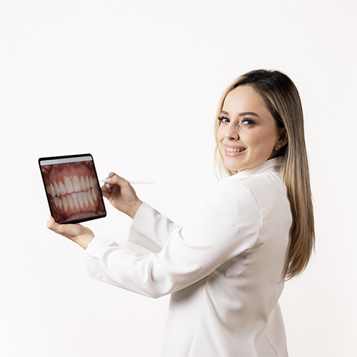 Una dentista sonriente muestra una imagen de alta resolución de unos dientes en una tableta en nuestra clínica dental avanzada.