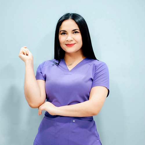 Dra. Leyri Estrada posa en uniforme quirúrgico morado, lista para brindar atención experta en la clínica dental.