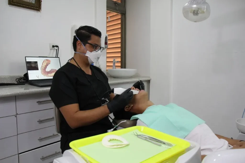 Odontólogo realizando un escaneo intraoral a un paciente durante una moderna consulta dental con tecnología digital.